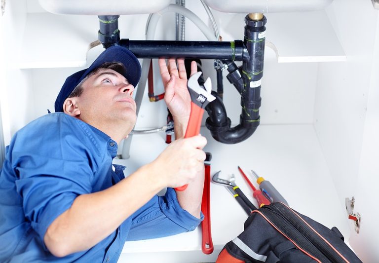 Handsome professional plumber doing sink reparation. Contractor.